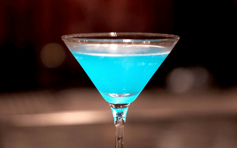 Glasses of blue envy cocktail in a wooden surface