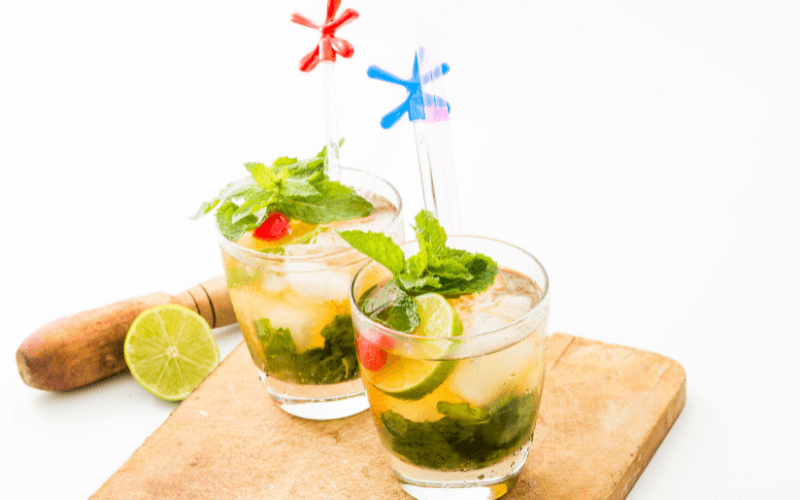 Glasses of garnished mint julep in a wooden tray