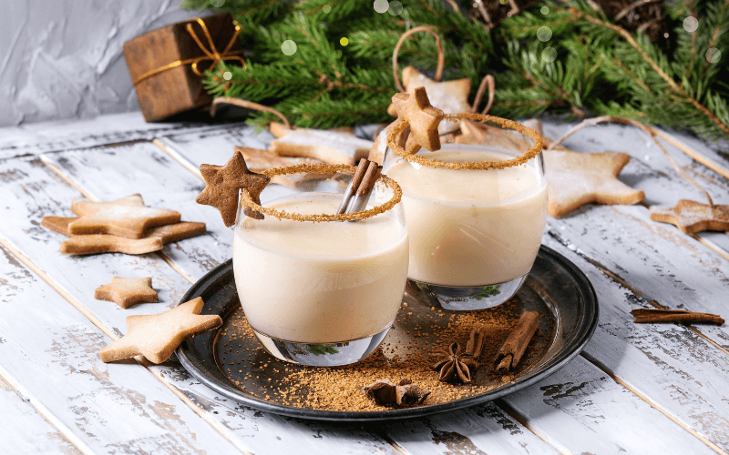 Glasses of eggnog white russian in a tray smeared with gingerbread crumbs