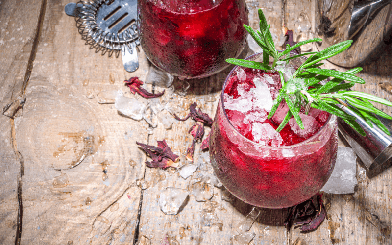 Glasses of hibiscus smash with rosemary in a wooden table