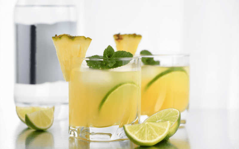 Glasses of pineapple tequila sour with fresh lime in a white background