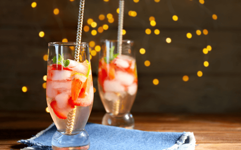 Glasses of strawberry spritzer with blurred lights background