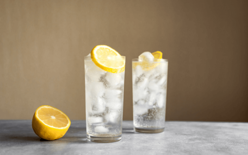 Glasses of tequila collins with lemon in a marble background