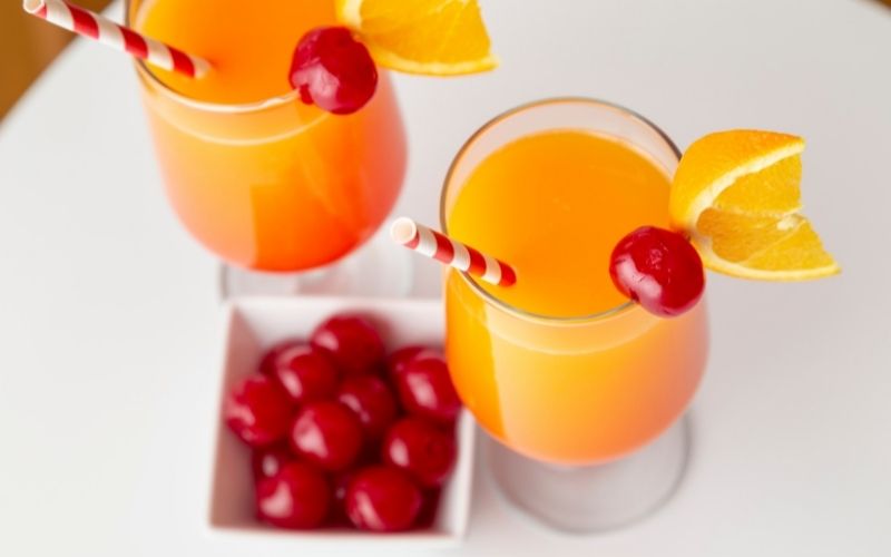 Glasses of tequila sunrise with maraschino cherries as garnish