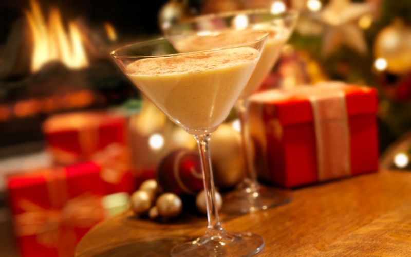 Glasses of white chocolate eggnog martini on a Christmas background