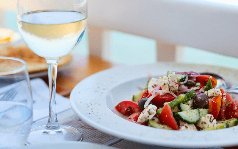 Greek salad with white wine on a table