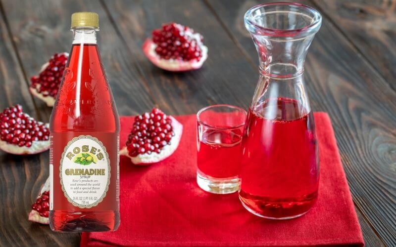 Grenadine syrup in a bottle and glass with pomegranate