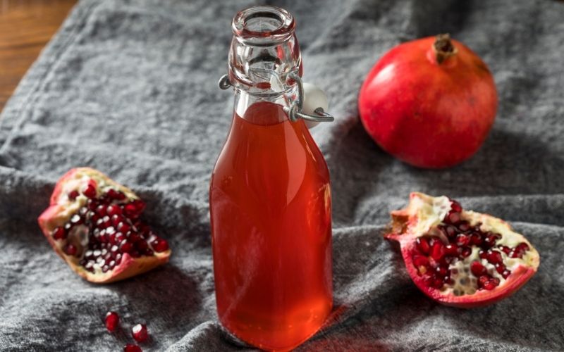 Grenadine syrup in a bottle with fresh pomegranate