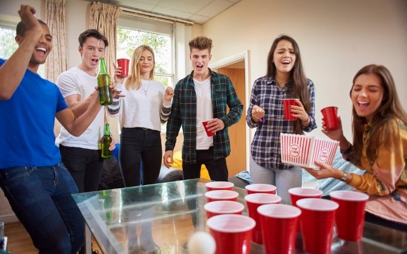 Group of friends drinking and playing beer pong