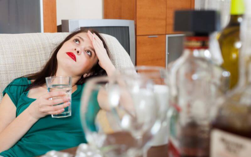 Hungover woman holding a glass of water