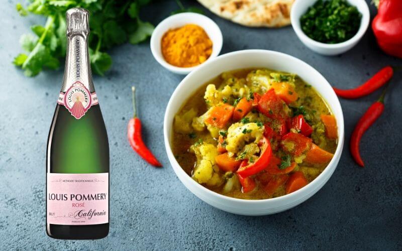 Indian vegetable curry and a sparkling rose bottle