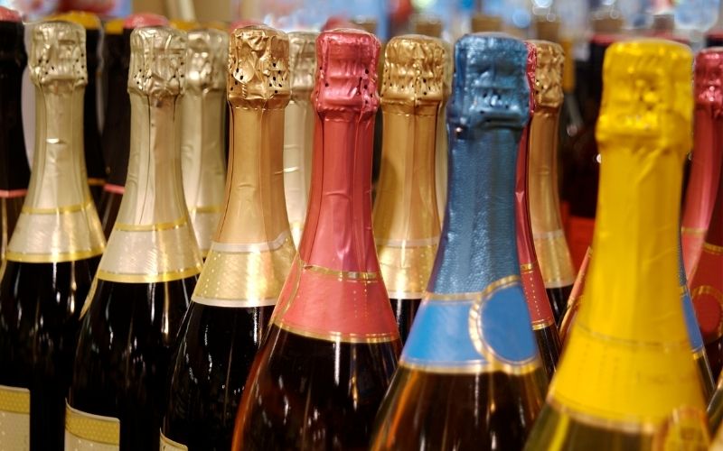 Lined up Different Colored Champagne Bottles