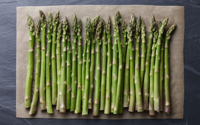 Lined up asparagus on a baking sheet