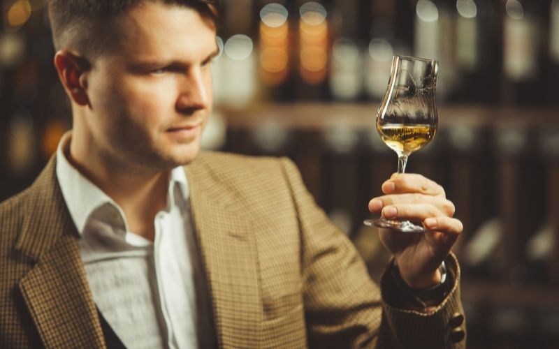Male sommelier tasting whiskey at cellar