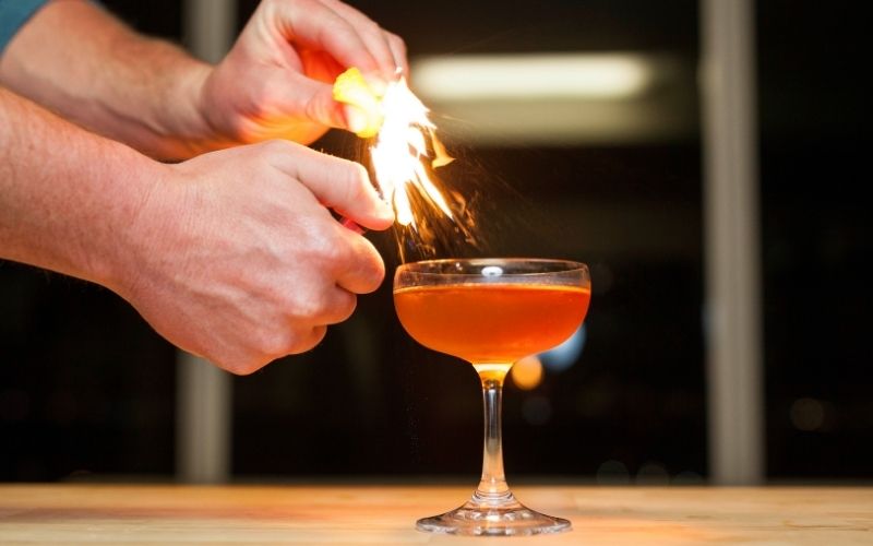 Man flaming an orange peel on a cocktail
