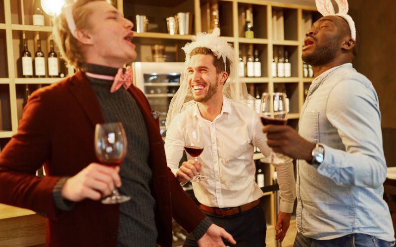 Man wearing a wedding veil and two friends with bunny ears at a bar