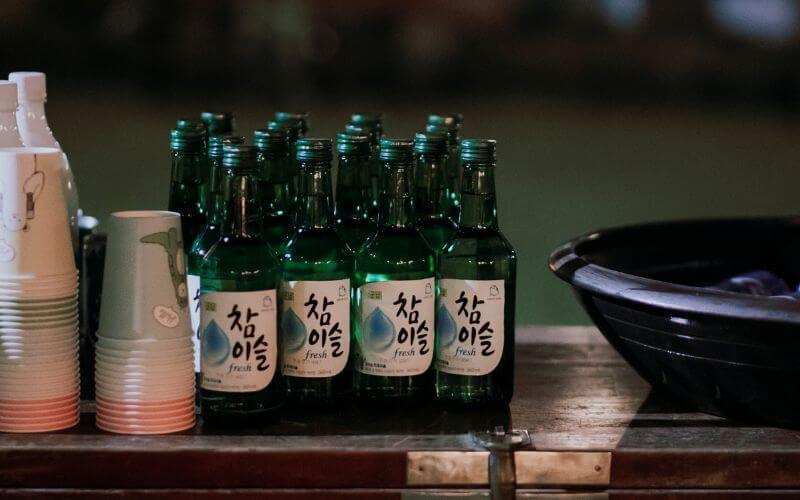 Multiple bottles of Soju and cups on the table