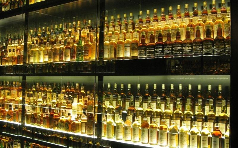 Numerous bottles of whiskey on a cabinet