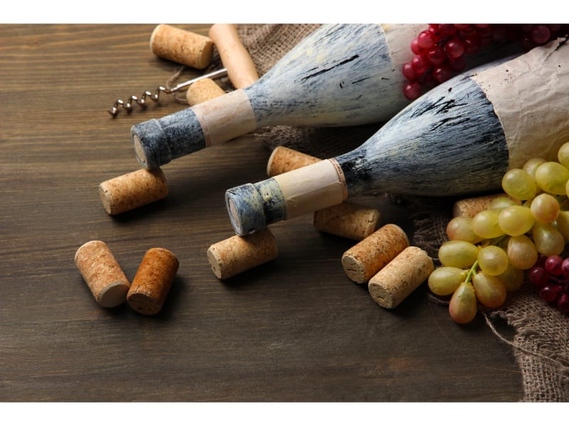 Old Bottles of Wine, Grapes and Corks on Wooden Background