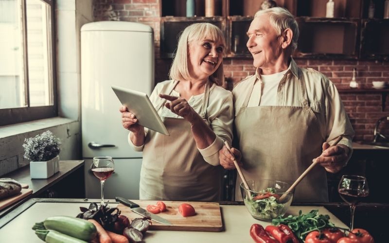 Old couple making salad in the kitchen