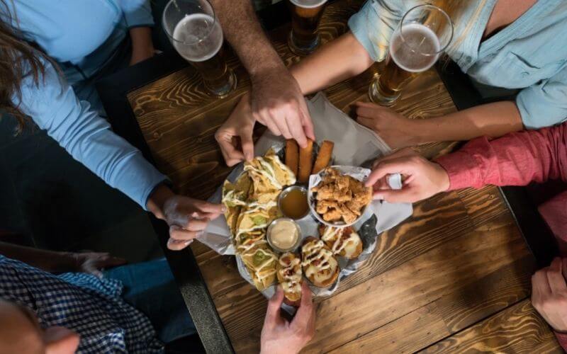 People drinking beer while eating finger foods