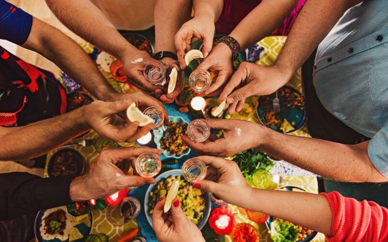 People drinking tequila over a table of food