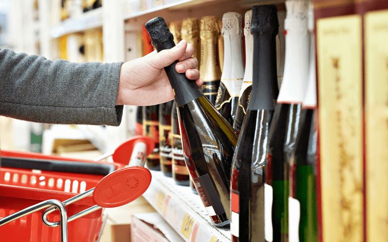 Person grabbing a bottle of sparkling wine at a store