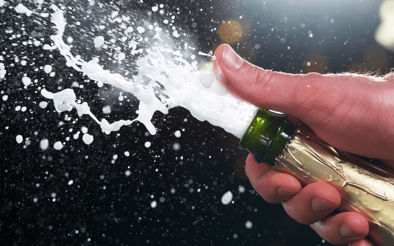 Person's hand popping a bottle of Champagne