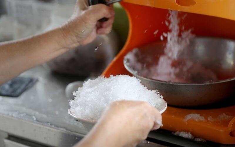 Person shaving ice using a machine