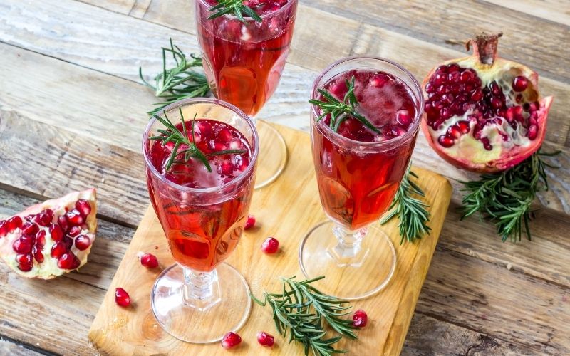 Pomegranate Fizz on cutting board with rosemary 