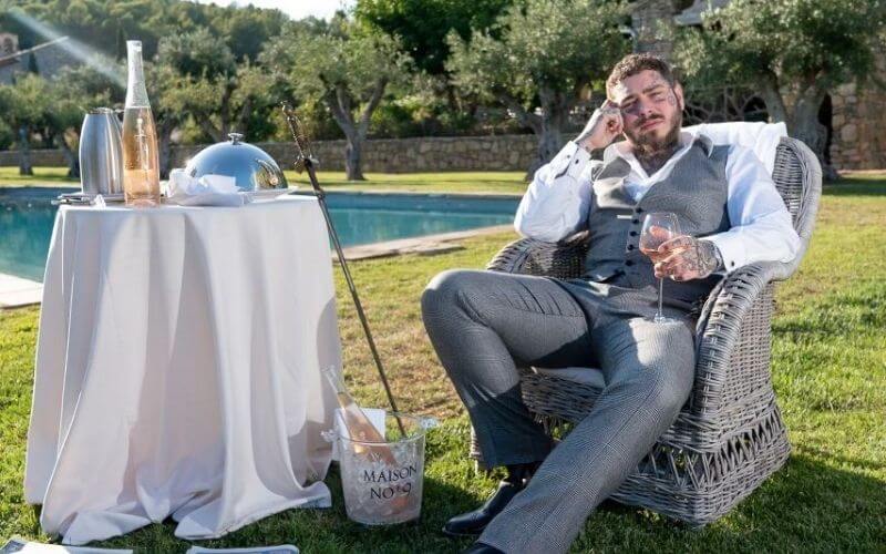 Post Malone sitting in a yard with his wine - Image by Maison 9 Wine