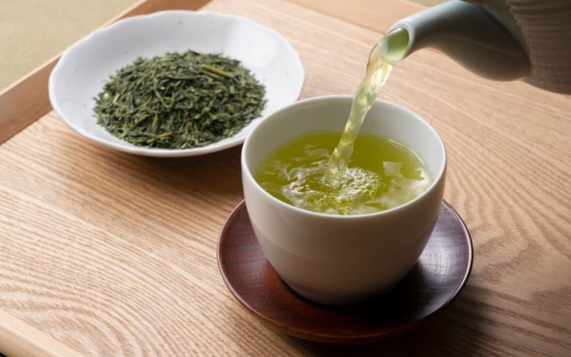 Pouring green tea into a teacup