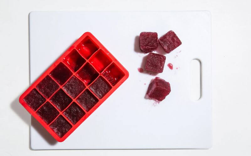 Red wine ice cubes in a tray and cutting board