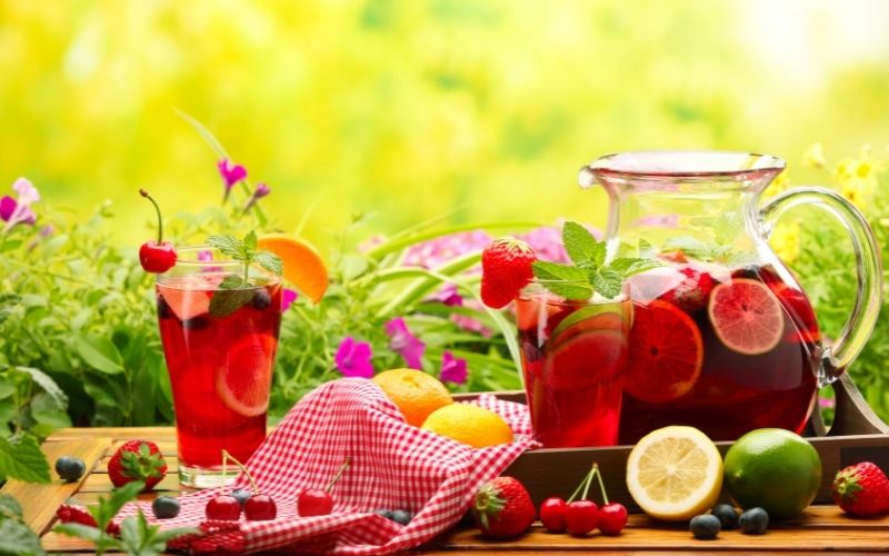 Brandy sangria in pitcher and glasses on a wooden tray