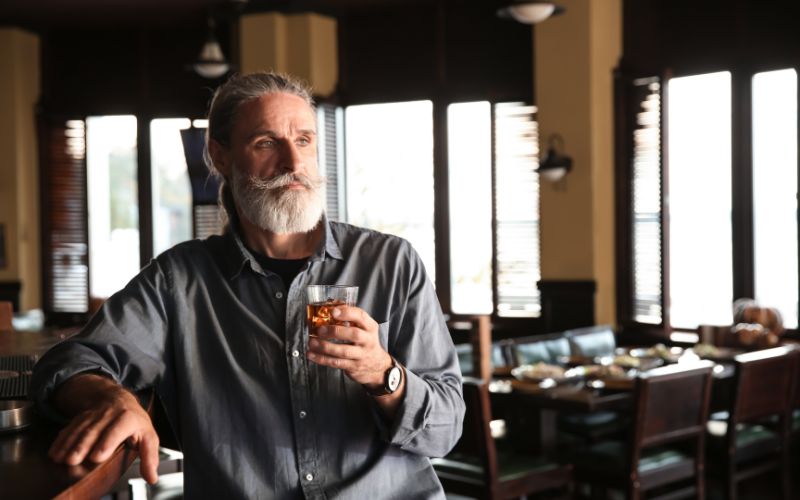 Senior man drinking alcohol in a pub