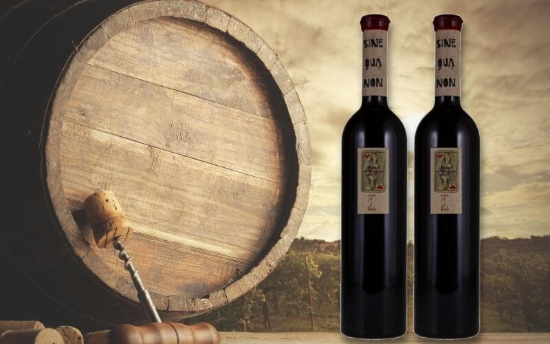 Sine Qua Non 'Queen of Hearts beside a wine barrel