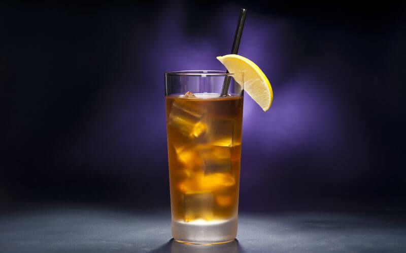 Tea-infused vodka cocktail with ice and lemon wedge