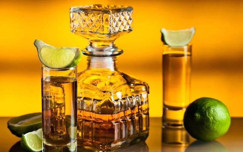 Tequila decanter beside two shot glasses with lime chaser