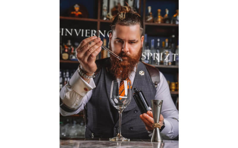 The Cocktail Butcher measuring a liqueur 