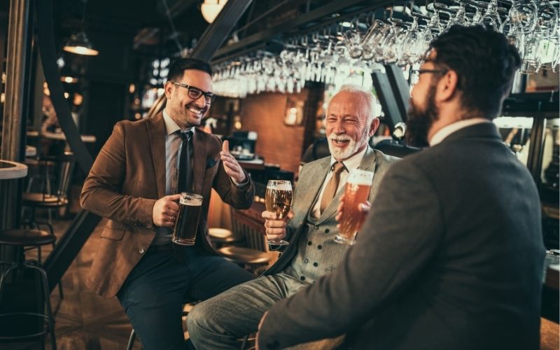 Three men talking while enjoying beers in a bar