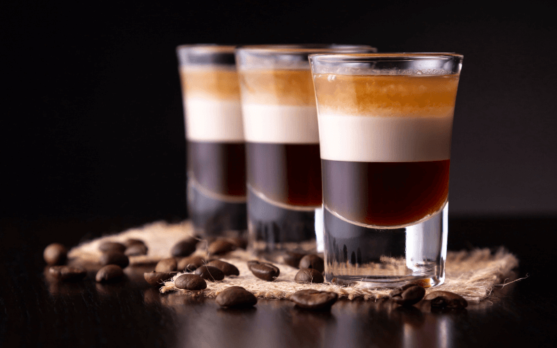 Three shot glasses of duck fart cocktail in a dark background