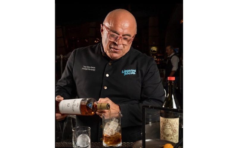 Tony Abou Ganim pouring a drink into a glass