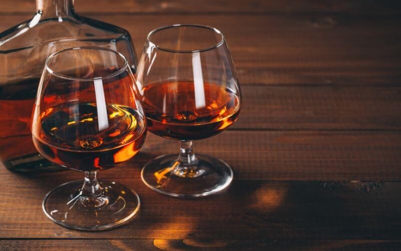 Two glasses of Cognac and bottle on the wooden table