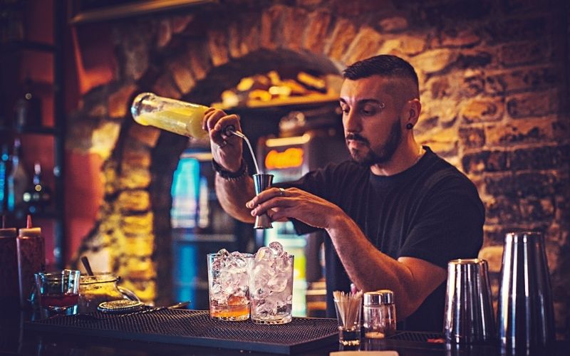 Bartender pouring a liquor bottle into a jigger