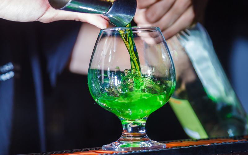 Bartender pouring absinthe into a glass