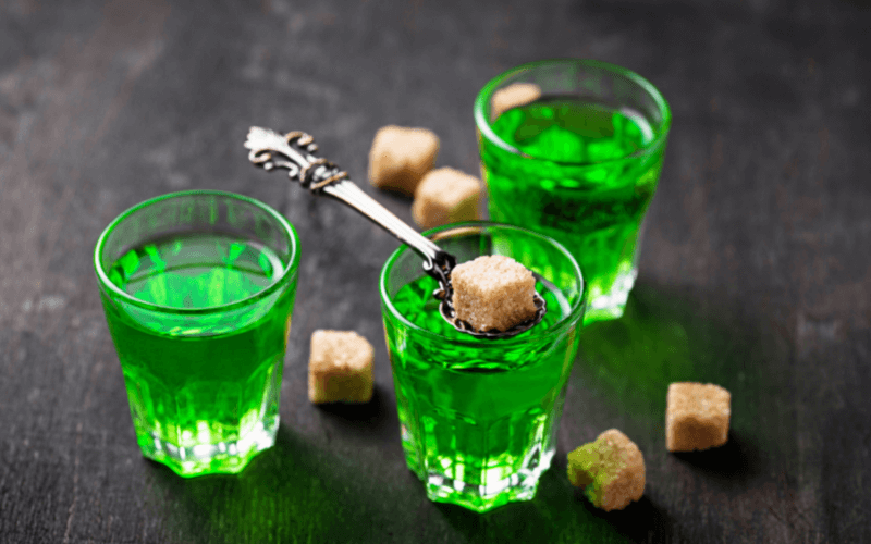 Three glasses of absinthe with absinthe spoon and sugar cubes
