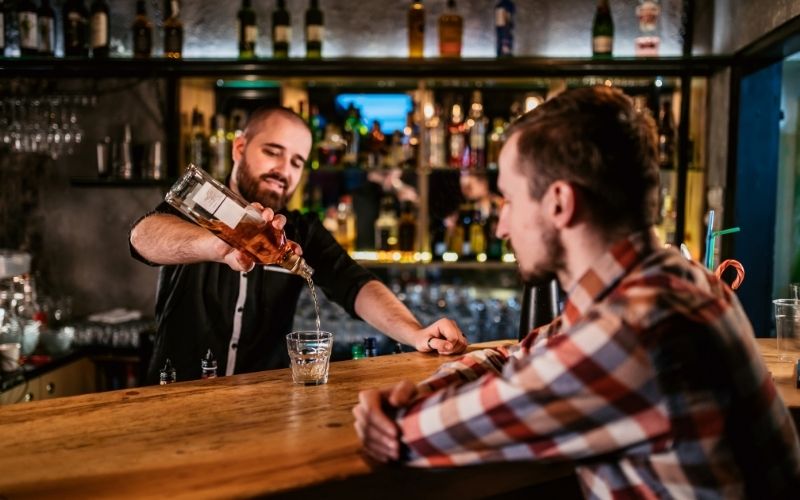 Bartender pouring a bottle of whiskey