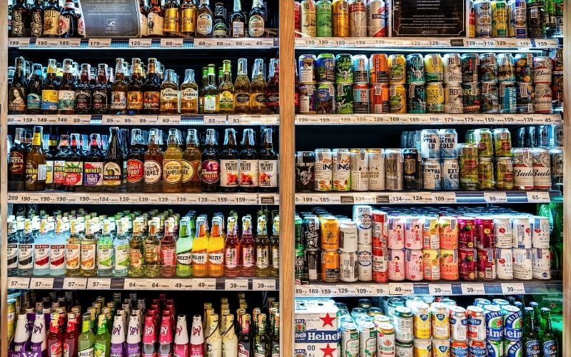 Various cans and bottles of beer in a grocery shelf