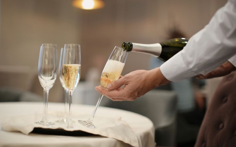 Waiter Pouring Champagne into Glasses