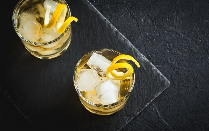 Whiskey on the rocks garnished with lemon twists